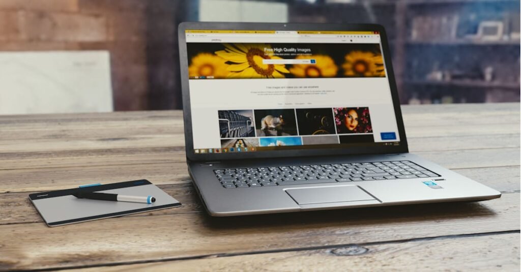 Laptop with open webpage on wooden desk, accompanied by tablet and pen, representing digital work setup.